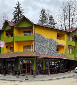 a yellow and green building with tables and chairs at Pensiunea Izvoare Olanesti 3*** in Băile Olăneşti