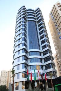 Al Salam Hotel في الكويت: مبنى طويل مع أعلام أمامه