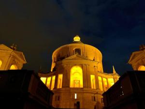 a building lit up at night with a clock on it at House of Alchemy in Bologna