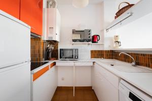 uma pequena cozinha com armários brancos e detalhes em laranja em AS11677 - Marina de type p3 avec parking privé et appontement em Le Grau-du-Roi
