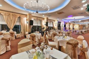 a restaurant with white tables and chairs and a chandelier at Hotel Princess in Bar +37 photos