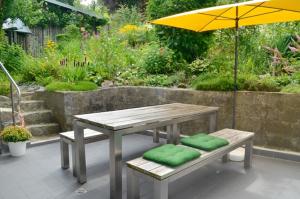 a picnic table and bench with an umbrella in a garden at B&B Brandholz in Goldkronach