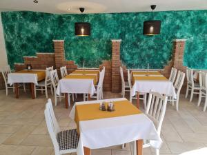 a restaurant with tables and chairs and a green wall at Vánkos & Eszcájg in Újhartyán