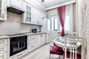 cocina con armarios blancos, mesa y ventana en Raisson Ahotel F107, en Astana