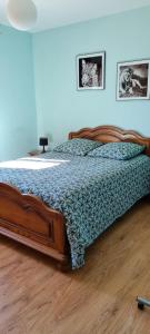 een slaapkamer met een houten bed met een blauw dekbed bij Maison au calme, grand jardin in Lailly-en-Val