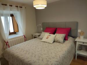 a bedroom with a large bed with red pillows at La Antigua Muralla in Burgos