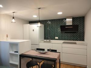 a kitchen with white cabinets and a table with chairs at La Antigua Muralla in Burgos