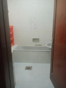 Baño blanco con bañera y lavamanos en Furnished room just 1 minute to Al ain mall, en Al Ain