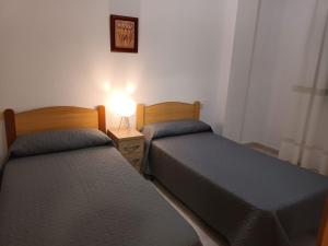 duas camas num quarto com um candeeiro numa mesa de cabeceira em Apartamentos Parada em Oropesa del Mar
