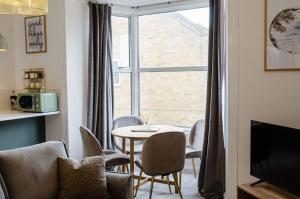 a living room with a table and chairs and a window at Central Chic Margate Apartment, edge of Old Town! in Kent