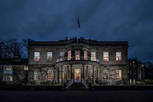 um grande edifício de pedra com uma bandeira no topo à noite em Wood Hall Hotel & Spa em Wetherby