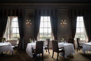 a dining room with tables and chairs and windows at Wood Hall Hotel & Spa in Wetherby