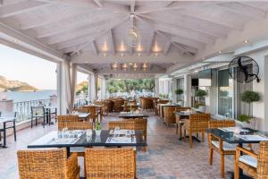 a restaurant with tables and chairs and a view of the ocean at Odysseus Hotel in Paleokastritsa
