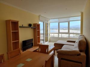 uma sala de estar com um sofá, uma mesa e uma televisão em Apartamento Damián em Foz