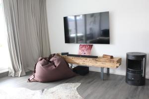 a living room with a table and a television on a wall at Hochwertige Sonneninsel mit Aussicht in Tettnang
