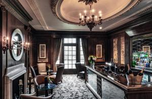 un bar in una stanza con lampadario a braccio di Wood Hall Hotel & Spa a Wetherby