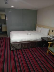 a large bed in a hotel room with a desk at de rěve Express Hotel in Chiayi City
