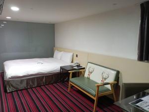 een hotelkamer met een bed en een stoel bij de rěve Express Hotel in Chiayi City