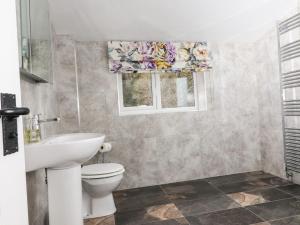 a bathroom with a toilet and a sink and two windows at Paradise Cottage in Harrogate +17 photos