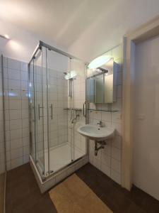 un bagno con doccia in vetro e lavandino di Gasthof Grüner Baum a Kirchberg am Wechsel