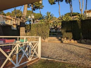 einen Holzzaun vor einem Haus mit Palmen in der Unterkunft Apartamento Cala del Pi in Platja  d'Aro