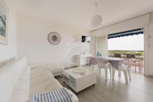ein weißes Wohnzimmer mit einem weißen Sofa und einem Tisch in der Unterkunft AS13357 - P3 face à la plage sans route à traverser, proche centre ville avec parking privé in Le Grau-du-Roi