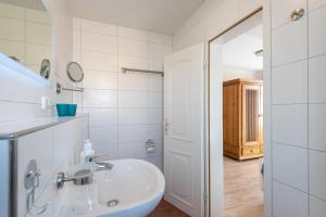 a white bathroom with a sink and a mirror at Sölring Hüs, App 3 in Wenningstedt