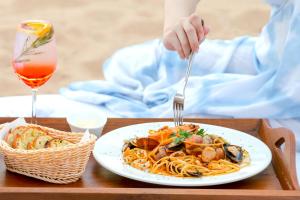 uma pessoa a comer um prato de massa com um garfo em Pinnacle Grand Jomtien Resort and Beach Club - SHA Extra Plus em Praia de Jomtien