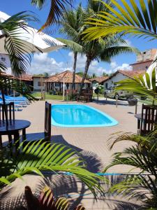 a swimming pool in a resort with palm trees at Pousada Luar in Santa Cruz Cabrália