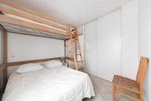 a bedroom with a bed and a wooden chair at AS14627 - P3 au coeur du Centre Ville avec parking privé in Le Grau-du-Roi