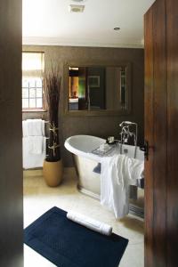 a bathroom with a bath tub and a mirror at Langshott Manor - Luxury Hotel Gatwick in Horley