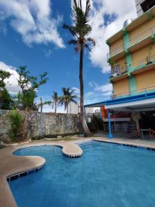 a swimming pool in front of a hotel with a palm tree at Metro Park Hotel - Cebu City in Cebu City