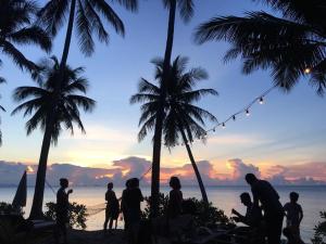 a group of people on a beach with palm trees at Jasmine & Tea House in Mae Nam