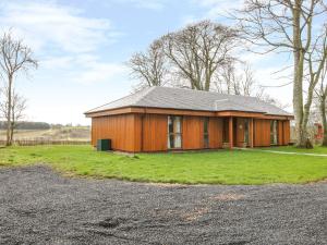 una pequeña casa de madera en un campo con entrada en Blackadder Lodge, en Duns