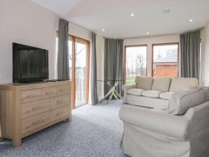 a living room with a couch and a flat screen tv at Blackadder Lodge in Duns