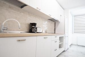 a kitchen with white cabinets and a sink at White home in Timişoara +25 photos