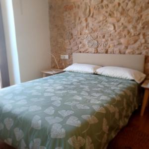 Bett in einem Zimmer mit einer Steinmauer in der Unterkunft Apartaments Casa el Metge in Prat de Comte