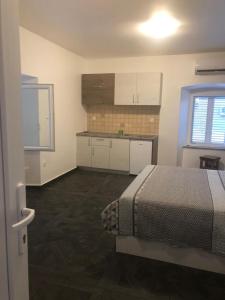 um quarto com uma cama e uma cozinha com armários brancos em Apartments Tonka em Zadar