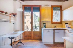 eine Küche mit weißen Geräten und einem großen Fenster in der Unterkunft Sleep y Stay Arab Baths Ático Apartment in Girona