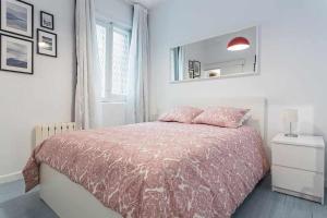 1 dormitorio con 1 cama con manta rosa y espejo en Apartamento confortable en Atocha, en Madrid