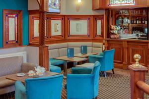 a restaurant with blue chairs and tables and a bar at Best Western Woodlands Hotel in Dundee