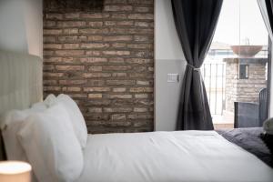 una camera con un letto bianco e un muro di mattoni di Arch Rome Suites a Roma