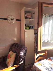 Habitación con silla, nevera y reloj en Apartamento Enzo, en La Franca