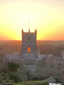 an old building with a sunset in the background at St Davids Gin & Kitchen - The Cathedral Villas in St. Davids