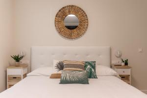 a bedroom with a white bed with a mirror on the wall at Nuevo y Luminoso en Plaza Moyua in Bilbao