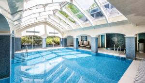 einen Pool in einem Gebäude mit Glasdecke in der Unterkunft Ettington Park Hotel, Stratford-upon-Avon in Stratford-upon-Avon
