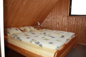 a bed in a room with a wooden wall at Szarvaskő Szérűskert vendégház in Szarvaskő +80 photos