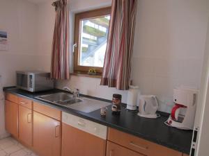 eine kleine Küche mit einem Waschbecken und einem Fenster in der Unterkunft Ferienwohnung Sonnenwiese in Wittenbeck