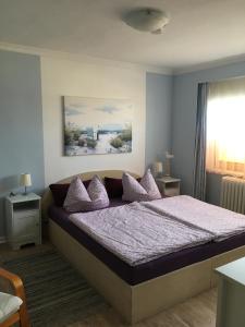 Schlafzimmer mit einem Bett mit lila Bettwäsche und Kissen in der Unterkunft Ferienwohnung Dünensand in Kühlungsborn