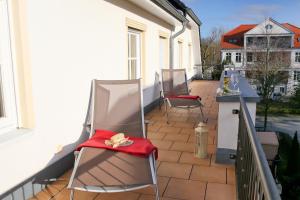 - un balcon avec 2 chaises et une couverture rouge dans l'établissement Ferienwohnung Katharina - Urlaub mit Strandkorb, à Kühlungsborn